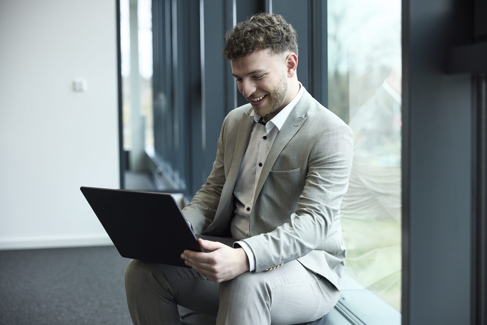 Lukas Strobel sitzt mit Laptop am Fenster